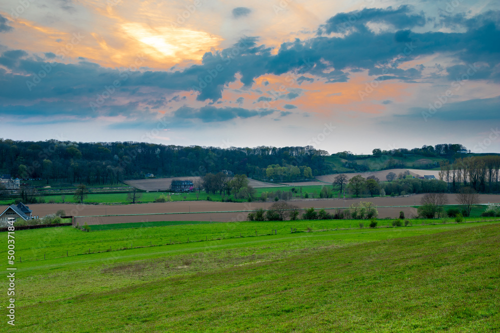 sunset view over the rolling hills  and meadows of the most southern province of the Netherlands with a dramatic cloudscape. This valley is crossed by a small river called the Jeker