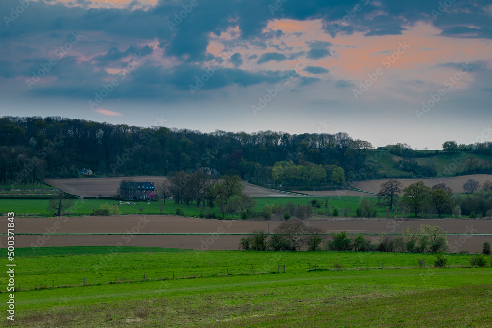 sunset view over the rolling hills  and meadows of the most southern province of the Netherlands with a dramatic cloudscape. This valley is crossed by a small river called the Jeker