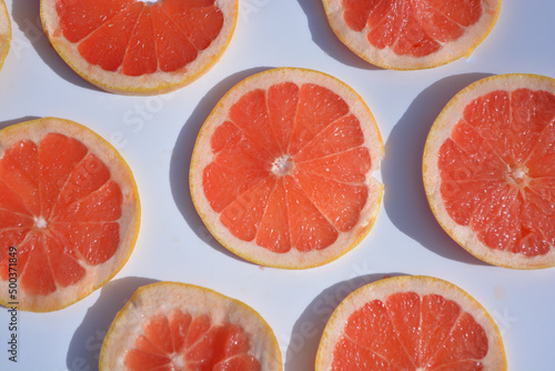 Colorful fruit pattern of fresh grapefruit slices on white background. Minimal flat lay concept.