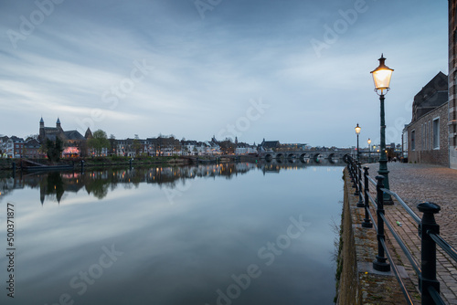 Long exposure view of the historic skyline of Maastricht with a view over the river Meuse and the old roman bridge with on the side the typical street lights of the inner city. © KimWillems