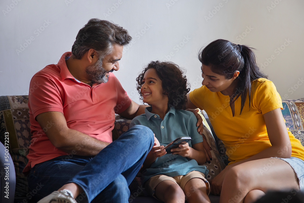 Family watching smartphone and having fun together in living room Family watching smartphone and having fun together in living room