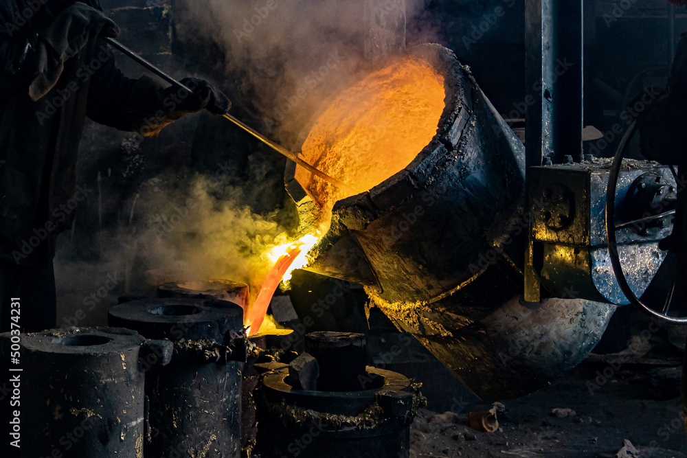 Foundry production. A worker with a special tool stirs the molten metal in a casting ladle Foundry production. A worker with a special tool stirs the molten metal in a casting ladle