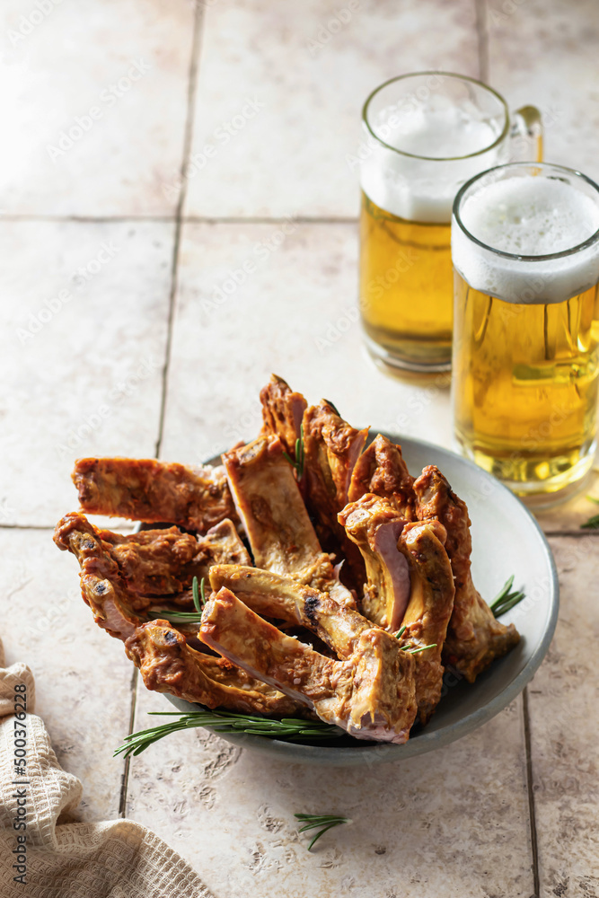 Smoked pork ribs with rosemary, beer and napkin on pink tile background