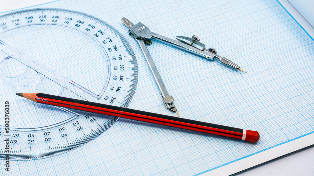On blue graph paper are compasses, protractor, ruler, and a pencil On blue graph paper are compasses, protractor, ruler, and a pencil