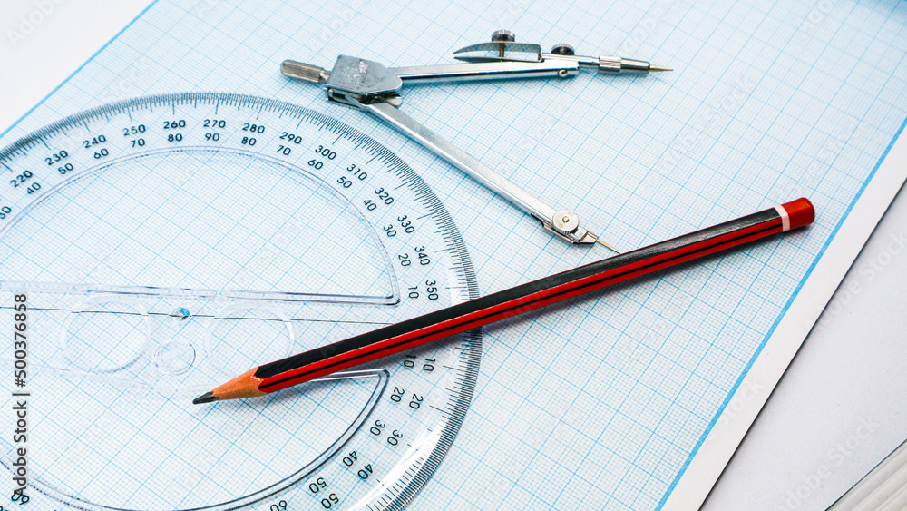 On blue graph paper are compasses, protractor, ruler, and a pencil On blue graph paper are compasses, protractor, ruler, and a pencil