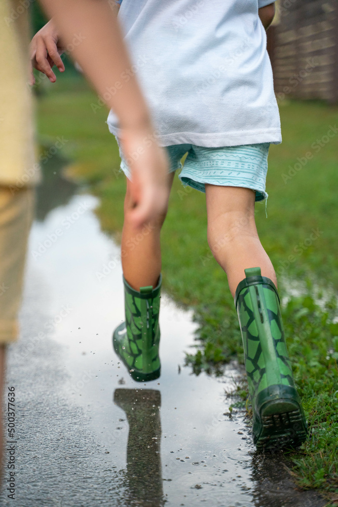A cheerful child runs through the puddles after the rain on a warm day A cheerful child runs through the puddles after the rain on a warm day