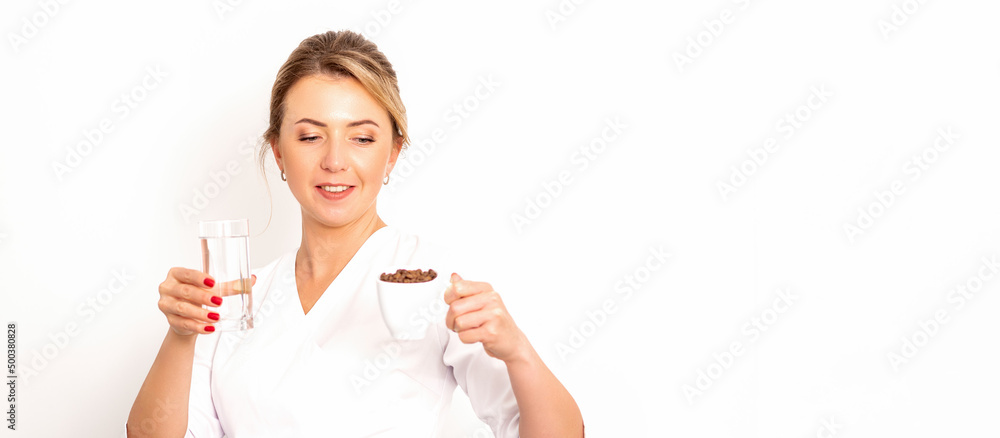 Coffee with water. The female nutritionist holds a cup of coffee beans and a glass of water in her hands on white background Coffee with water. The female nutritionist holds a cup of coffee beans and a glass of water in her hands on white background