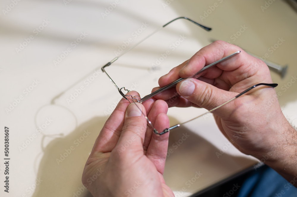 Installation of nose pads in glasses. A male technician repairs broken glasses Installation of nose pads in glasses. A male technician repairs broken glasses