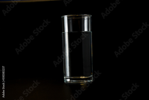 A clean glass glass glass with water on a black background. Side view
