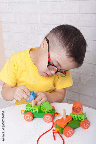 Motor therapy. Boy with down syndrome playing with toy and doing threading activities for hand therapy