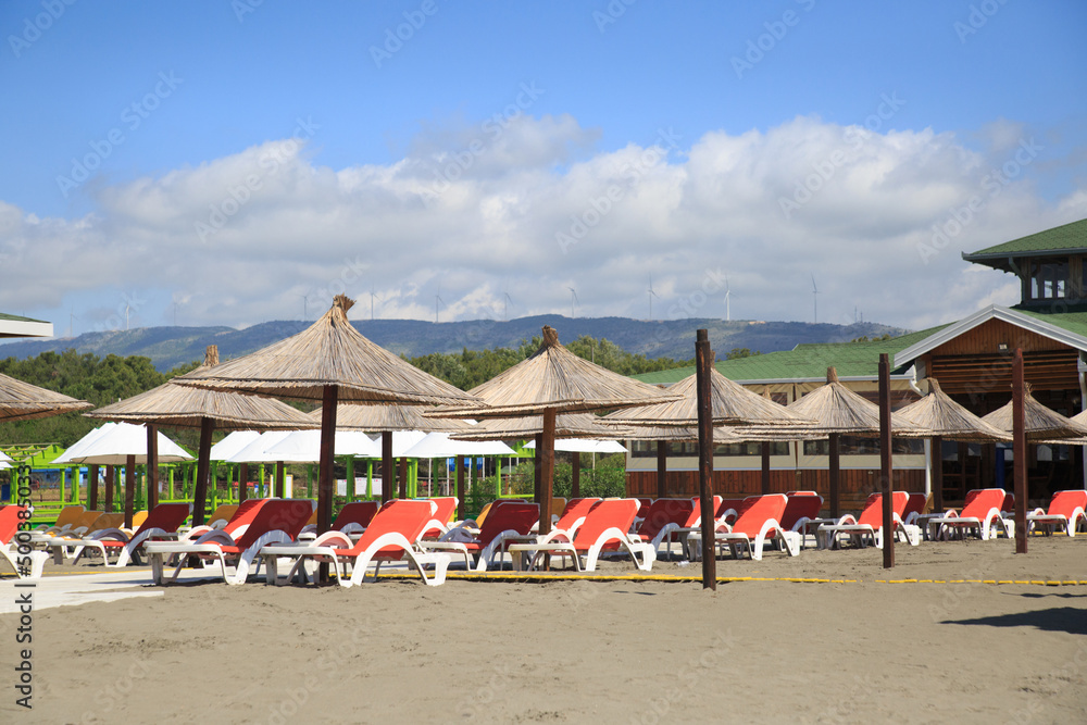 Beach with umbrellas and sun loungers by the sea on a sunny day, Montenegro.