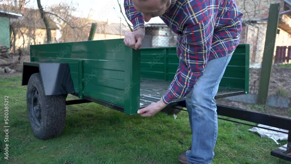 assemble a tractor trailer,man assembles a new trailer in the yard, agricultural machinery assemble a tractor trailer,man assembles a new trailer in the yard, agricultural machinery