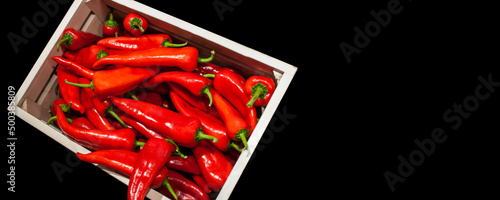 Spicy Chillli red peppers in wooden box on black background concept banner photo