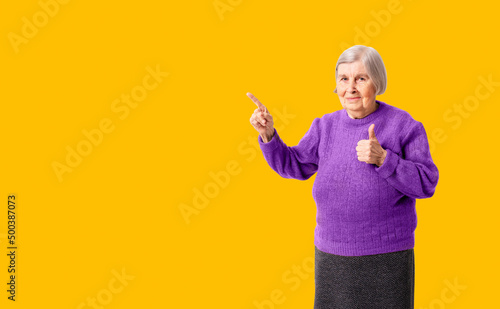 Cheerful octogenarian woman showing on empty place for copy space. Background for your promo or advertisement. Studio shoot.