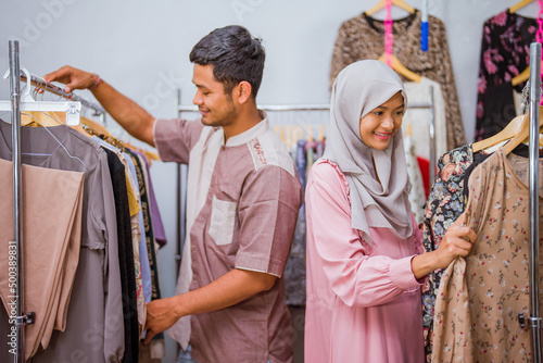beautiful muslim woman shopping some dress for idul fitri with her husband