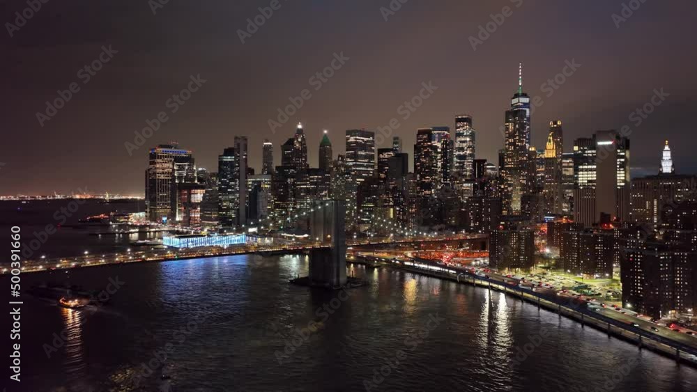Brooklyn Bridge lights at night with Manhattan skyline buildings on water NYC Brooklyn Bridge lights at night with Manhattan skyline buildings on water NYC