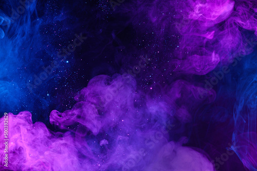 Shiny glitter particles in clouds of pink and blue neon colorful smoke abstract background