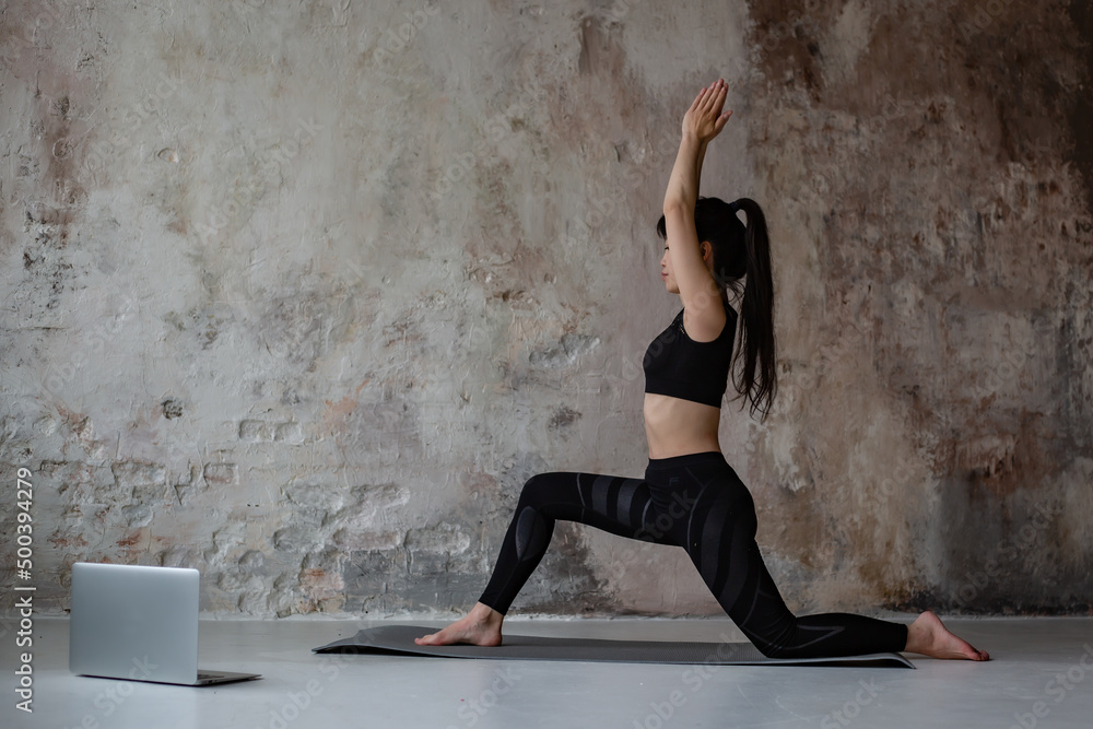 cute Asian girl with dark long hair in workout sportswear doing yoga online