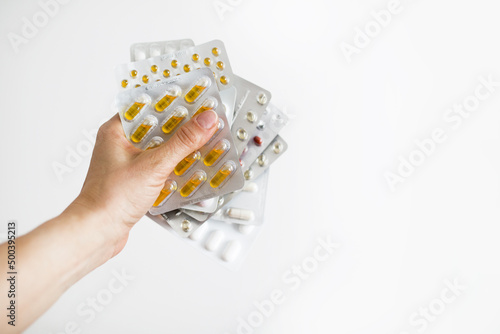 Dłonie trzymające blistry z lekarstwami i witaminami na białym tle