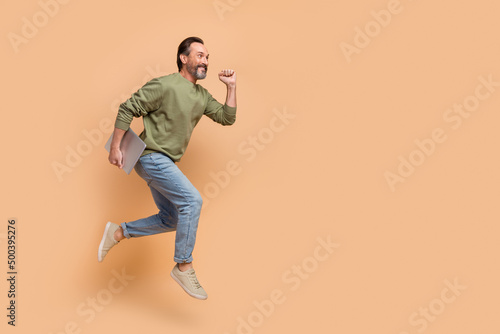 Full body photo of excited sporty man look empty space hurry rush isolated on beige color background
