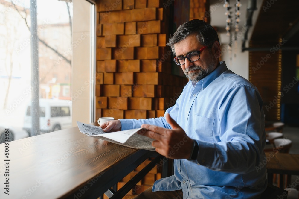 coffee break. man drinking coffee and reading newspaper in cafe bar