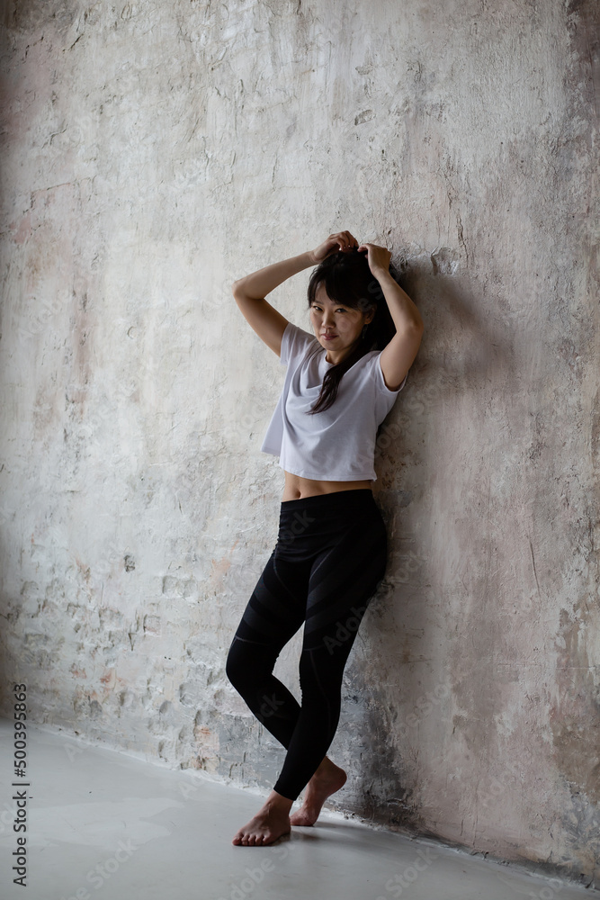 Fototapeta premium cute Asian girl with dark long hair is standing at the crafting wall 