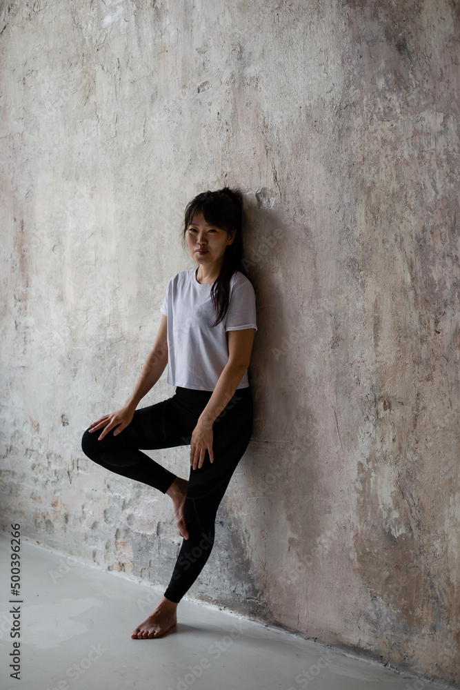 Fototapeta premium cute Asian girl with dark long hair is standing at the crafting wall 