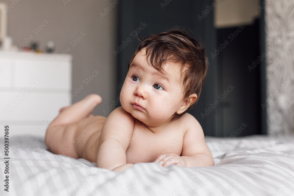 Portrait of naked baby lying on gray blanket at home, blurred background. Infant child crawl on tummy on bed in bedroom closeup, explore world. Selective focus, free copy space. Childcare concept. Portrait of naked baby lying on gray blanket at home, blurred background. Infant child crawl on tummy on bed in bedroom closeup, explore world. Selective focus, free copy space. Childcare concept.