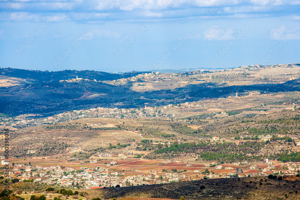 Spring Israeli landscape. View from the mountain to a hilly valley with villages, fields and gardens. Clouds cast shadows on the ground.