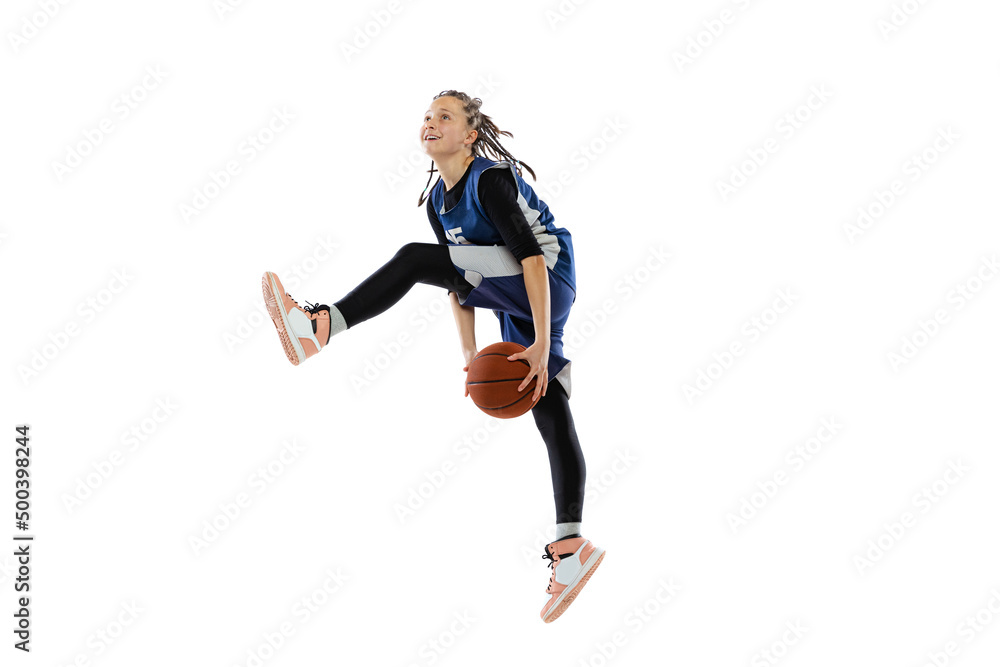 Dynamic portrait of teen girl, basketball player training, jumping with ball isolated over white studio background. Winning game