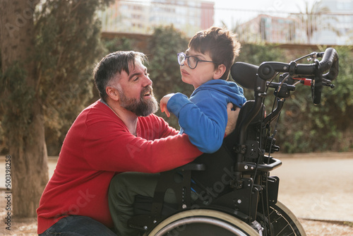 фотографія Loving father playing and enjoying time with his son with disability in a wheelchair