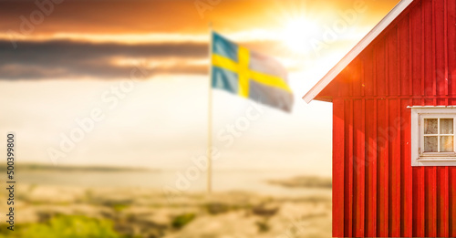 Rotes Schwedenhaus mit Schwedischer Flagge mit Sonnenlicht