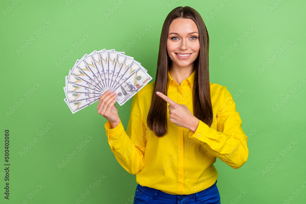 Photo of young lady indicate finger money ads decision choice recommend isolated over green color background Photo of young lady indicate finger money ads decision choice recommend isolated over green color background