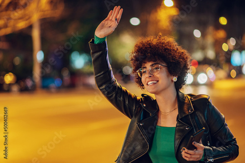 Foto Woman calling a taxi while standing on road in city