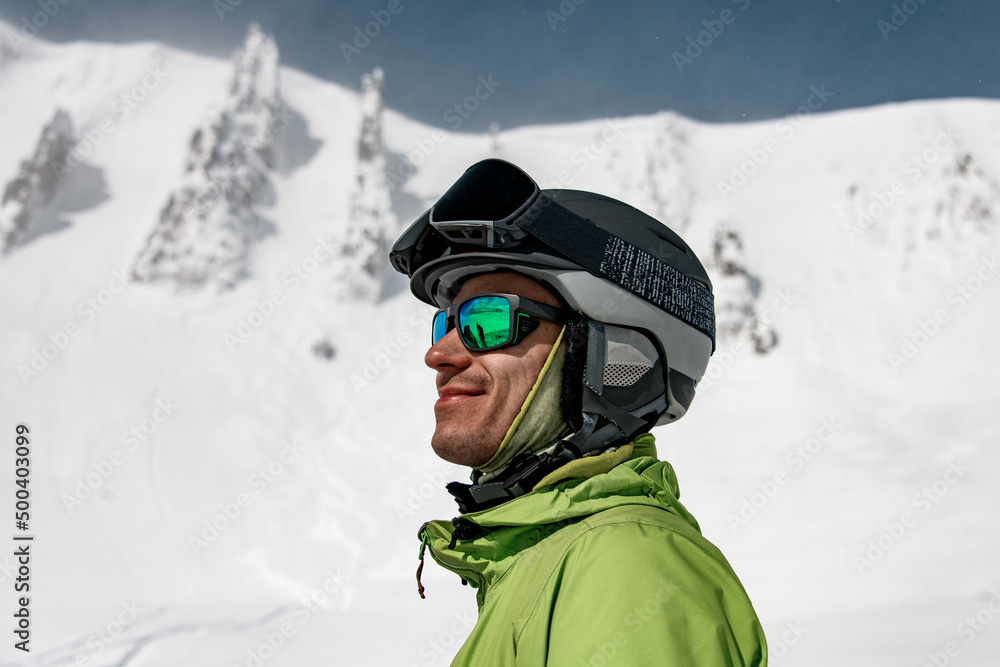 man in sunglasses and a ski helmet against the backdrop of snow-capped mountains man in sunglasses and a ski helmet against the backdrop of snow-capped mountains