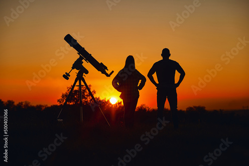 Couple stargazing together with a astronomical telescope.