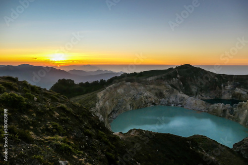Sunrise over the Kelimutu volcanic crater lakes in Moni, Flores, Indonesia. Skyline is bursting with orange. Turquoise color of the lake. Golden hour colours the surroundings. Beauty of the nature