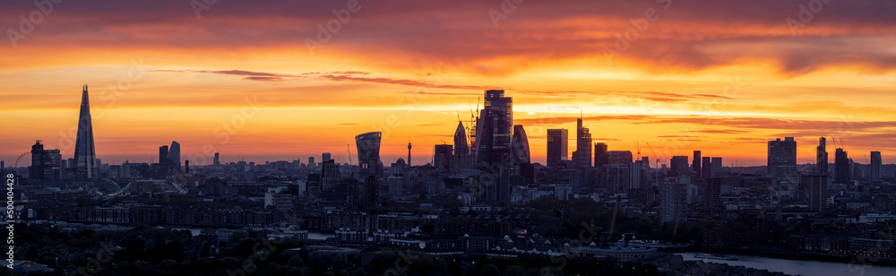 Panorama of the urban skyline of London during an intense sunset with City, river Thames and London bridge