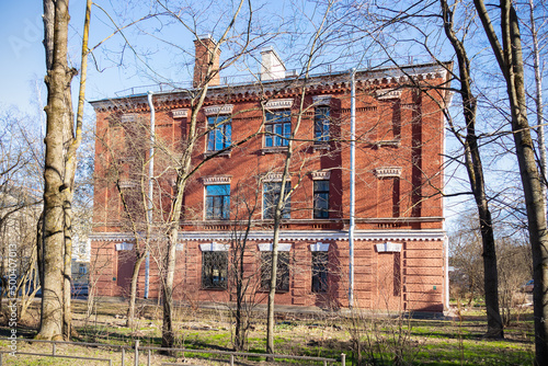 Retro three-storey red brick house behind bare trees