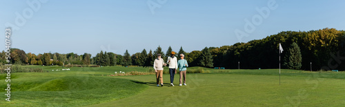asian man in sunglasses walking near senior multiethnic friends with golf clubs, banner.