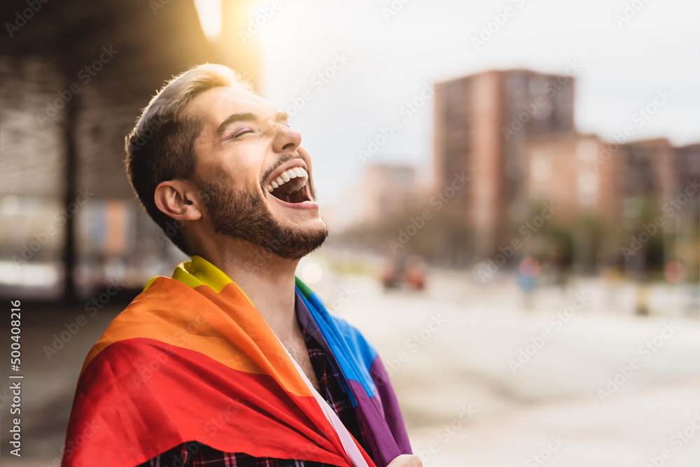 Happy gay man having fun holding rainbow flag symbol of LGBTQ community Happy gay man having fun holding rainbow flag symbol of LGBTQ community