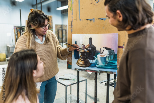 Teacher doing lesson of paint on canvas to young students arts university - Learning and culture concept