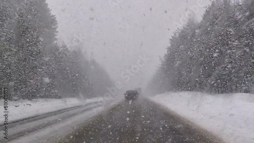 The car is driving along the highway through snow and blizzard. Video through the windshield on a winter storm.