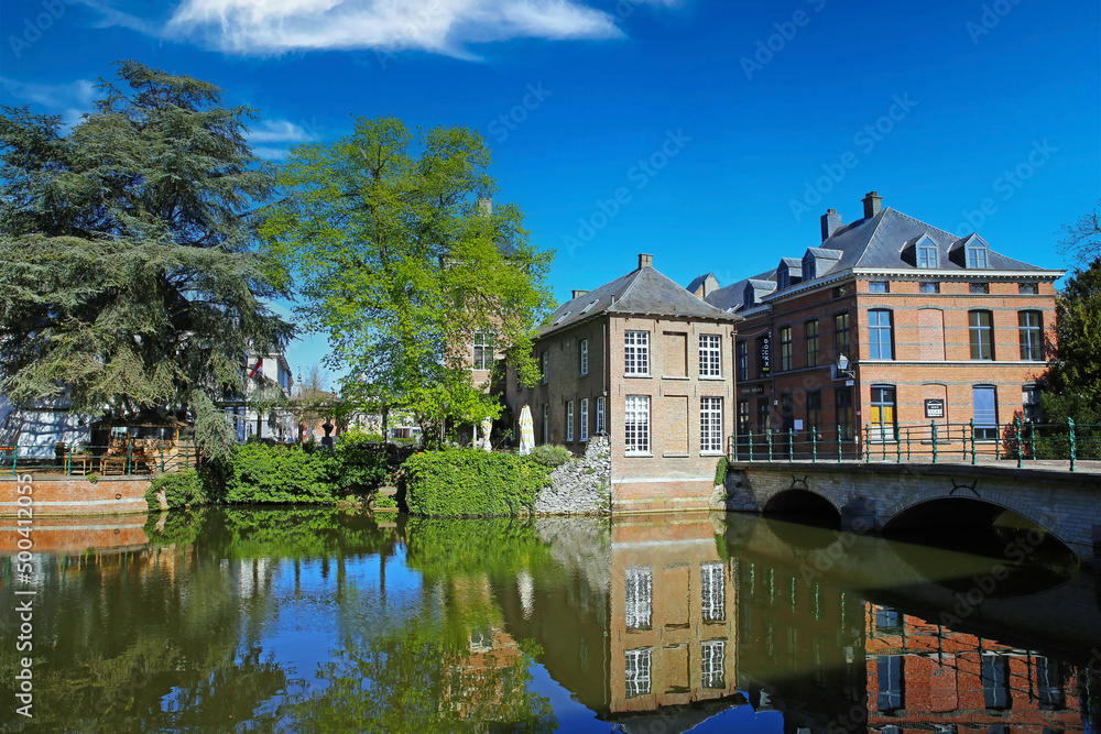 Lier, Belgium - April 9. 2022: View over water town moat on  medieval romantic old cityscape, ancient stone bridge, clear blue sky