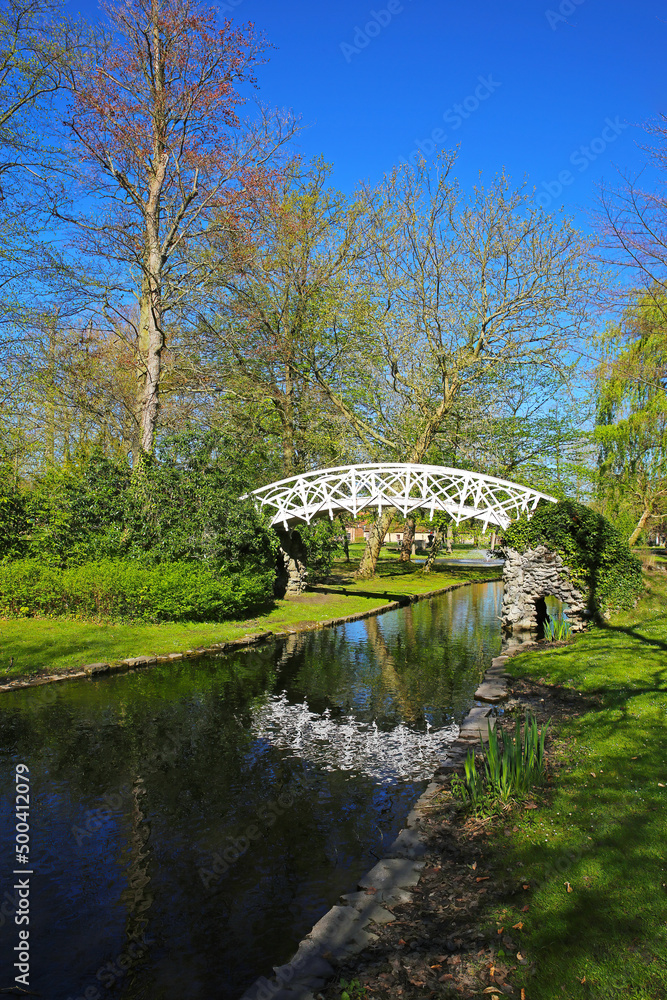 View on beautiful park in springtime with roamantic small white wood bridge, water creek and pond, blue sky - Lier, Belgium
