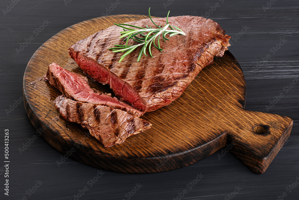 Beef steak and rosemary on a wooden background. Roast beef medium rare. Beef steak and rosemary on a wooden background. Roast beef medium rare.