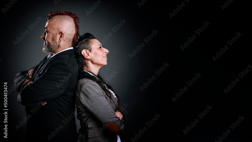 man and woman in punk style and elegant dresses, pose in a studio with their backs to each other. man and woman in punk style and elegant dresses, pose in a studio with their backs to each other.