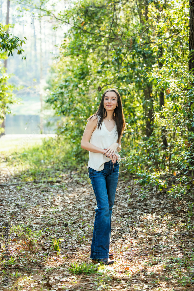 A beautiful serious teen brunette girl looking away from the camera towards the future in a wooded area in the spring