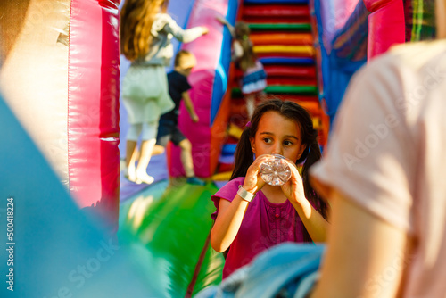 little girl drinks water on an inflatable trampoline