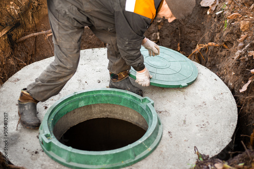 a utility worker opened a well hatch for sewerage maintenance and pumping out feces. Septic on a residential lot photo